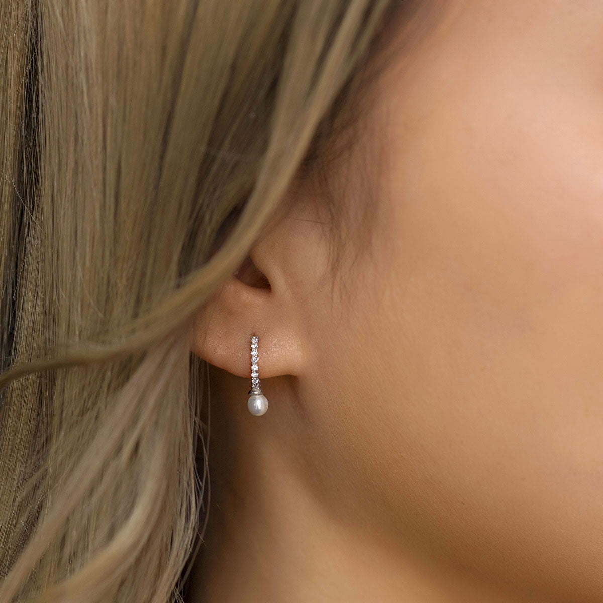 Silver Pearl Huggie earrings worn on ear